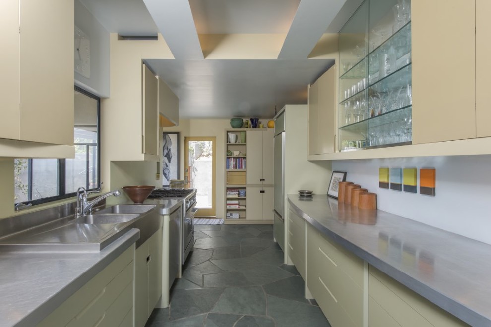 Idée de décoration pour une cuisine parallèle vintage avec un évier 2 bacs, des portes de placard jaunes, un électroménager en acier inoxydable et un sol en ardoise.