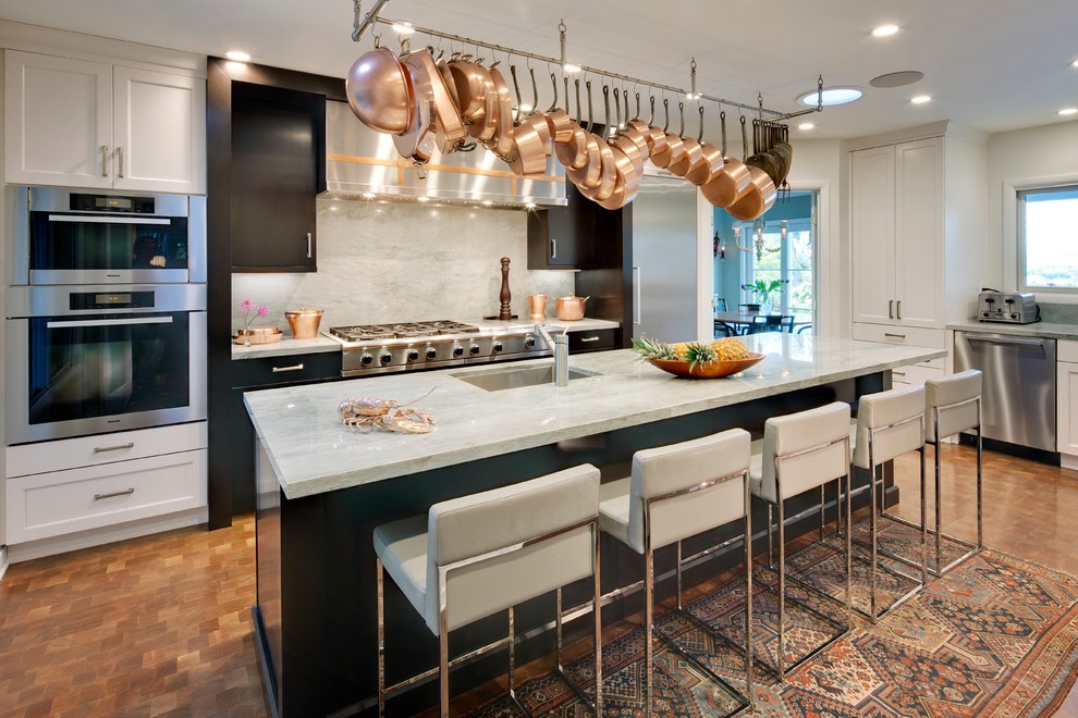 Example of a large transitional l-shaped medium tone wood floor enclosed kitchen design in Los Angeles with an undermount sink, white cabinets, quartzite countertops, gray backsplash, stone slab backsplash, stainless steel appliances, an island and shaker cabinets