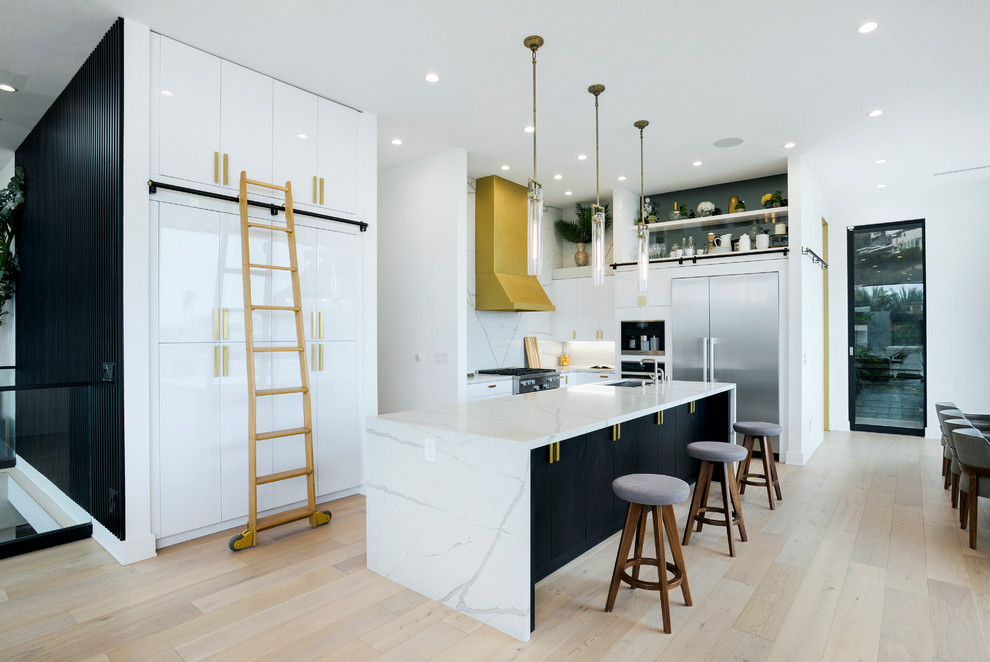 Große Moderne Küche mit flächenbündigen Schrankfronten, weißen Schränken, Küchenrückwand in Weiß, Küchengeräten aus Edelstahl, hellem Holzboden, Kücheninsel und weißer Arbeitsplatte in Los Angeles