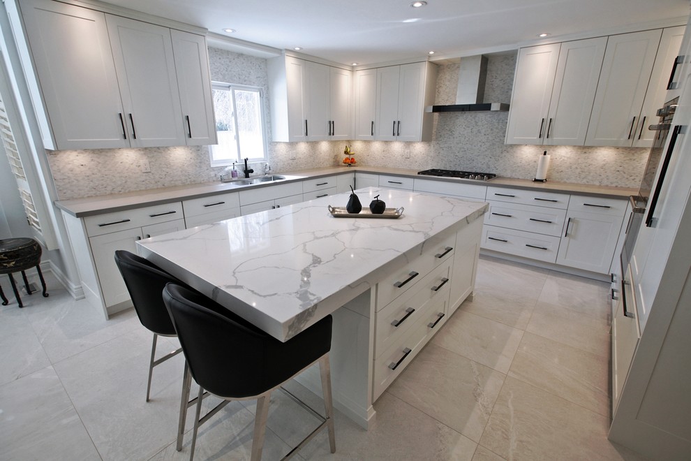 Design ideas for a large contemporary u-shaped enclosed kitchen in Toronto with a submerged sink, shaker cabinets, white cabinets, marble worktops, multi-coloured splashback, mosaic tiled splashback, stainless steel appliances, marble flooring, an island, beige floors and white worktops.