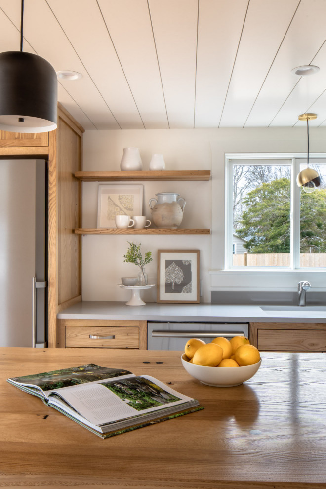 Foto på ett stort maritimt grå kök, med skåp i shakerstil, mellanmörkt trägolv, en köksö, brunt golv, en undermonterad diskho, bänkskiva i kvarts, grått stänkskydd och rostfria vitvaror