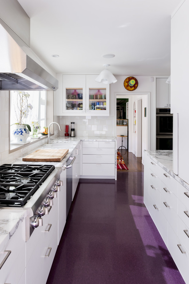 Идея дизайна: большая, узкая угловая кухня в стиле неоклассика (современная классика) с стеклянными фасадами, белыми фасадами, мраморной столешницей, техникой из нержавеющей стали и фиолетовым полом без острова