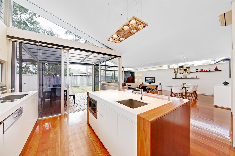 Offene, Einzeilige Moderne Küche mit Unterbauwaschbecken, flächenbündigen Schrankfronten, weißen Schränken, Küchengeräten aus Edelstahl, Kücheninsel und braunem Holzboden in Sydney