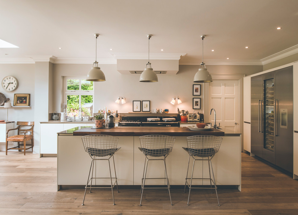 Mittelgroße Moderne Küche mit flächenbündigen Schrankfronten, beigen Schränken, Küchengeräten aus Edelstahl, braunem Holzboden, Kücheninsel und braunem Boden in Sonstige