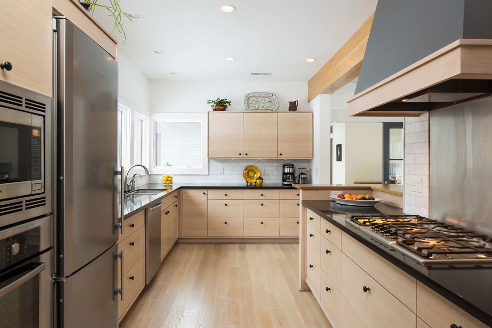 Enclosed kitchen - contemporary galley enclosed kitchen idea in Minneapolis with stainless steel appliances, an undermount sink, flat-panel cabinets, light wood cabinets, white backsplash and subway tile backsplash