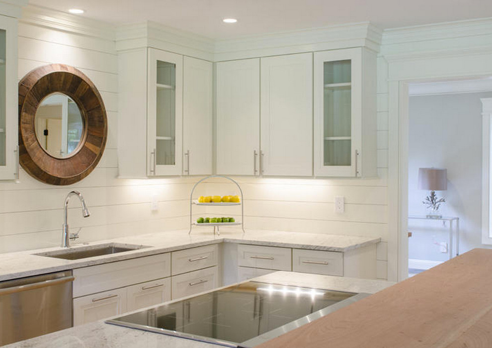 Inspiration for a large coastal l-shaped light wood floor kitchen remodel in Boston with a drop-in sink, glass-front cabinets, white cabinets, granite countertops, white backsplash, stainless steel appliances and an island