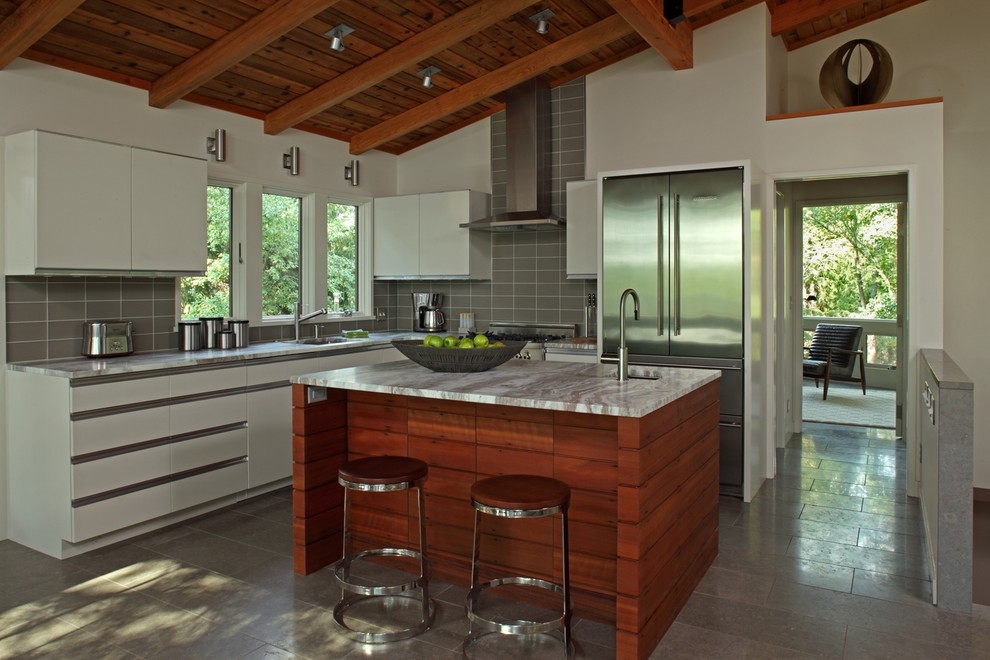 Immagine di una cucina a L contemporanea con ante lisce, ante bianche, paraspruzzi grigio e elettrodomestici in acciaio inossidabile