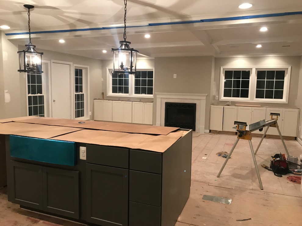 Inspiration for a large classic u-shaped kitchen in DC Metro with a belfast sink, shaker cabinets, white cabinets, engineered stone countertops, grey splashback, porcelain splashback, stainless steel appliances, medium hardwood flooring, an island, brown floors and white worktops.