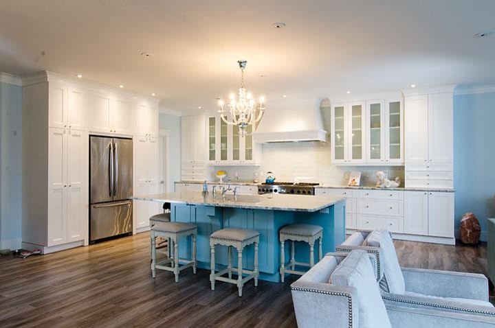 Klassische Küche mit weißen Schränken, Küchenrückwand in Weiß, Küchengeräten aus Edelstahl, braunem Holzboden und Kücheninsel in Montreal