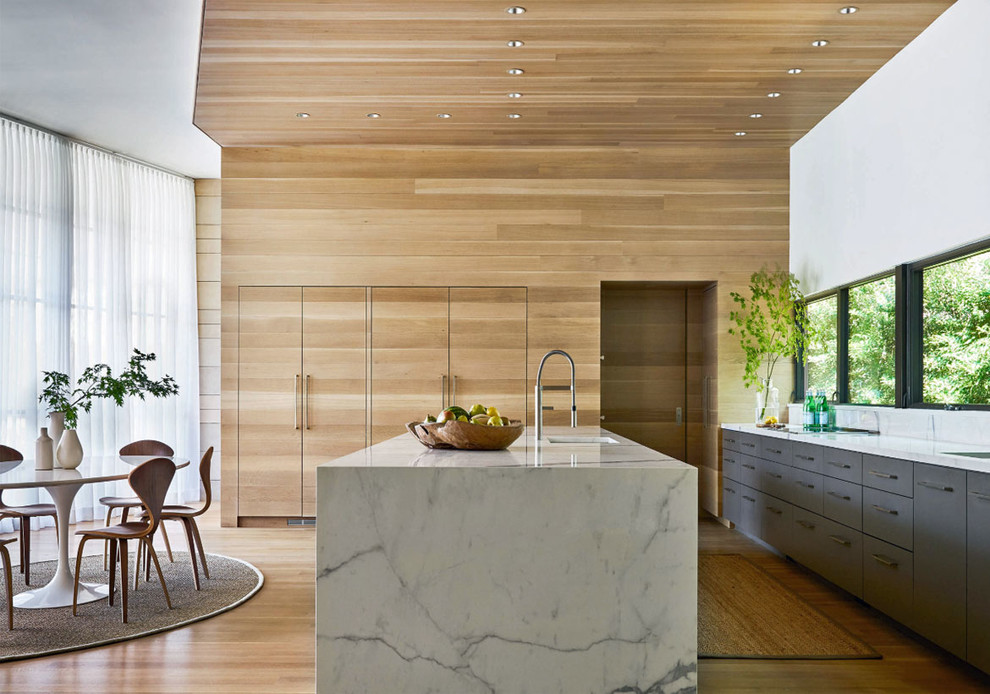 Esempio di una cucina minimal con lavello sottopiano, ante lisce, ante grigie, pavimento in legno massello medio, pavimento marrone e top bianco