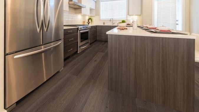 Example of a trendy medium tone wood floor eat-in kitchen design in Miami with an undermount sink, flat-panel cabinets, medium tone wood cabinets, quartz countertops, white backsplash, ceramic backsplash, stainless steel appliances and an island