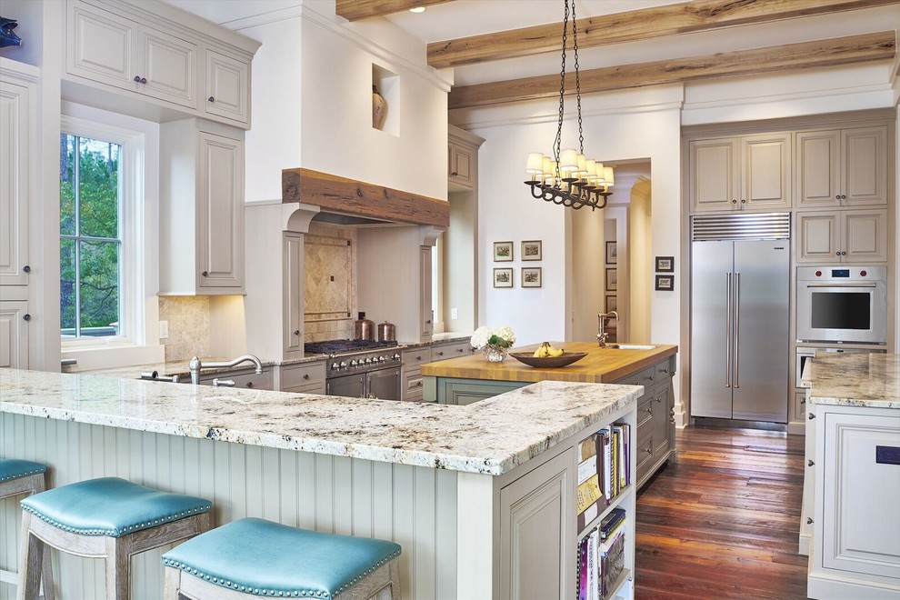 Large classic u-shaped kitchen/diner in Atlanta with raised-panel cabinets, beige splashback, stainless steel appliances, medium hardwood flooring, granite worktops, stone tiled splashback, multiple islands, grey cabinets and a belfast sink.