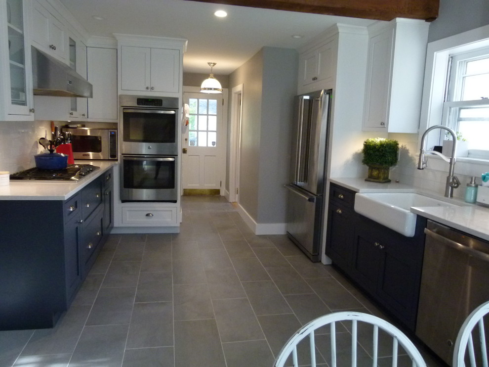 Inspiration for a mid-sized farmhouse galley concrete floor and gray floor eat-in kitchen remodel in New York with a farmhouse sink, shaker cabinets, white cabinets, solid surface countertops, white backsplash, terra-cotta backsplash, stainless steel appliances, no island and white countertops