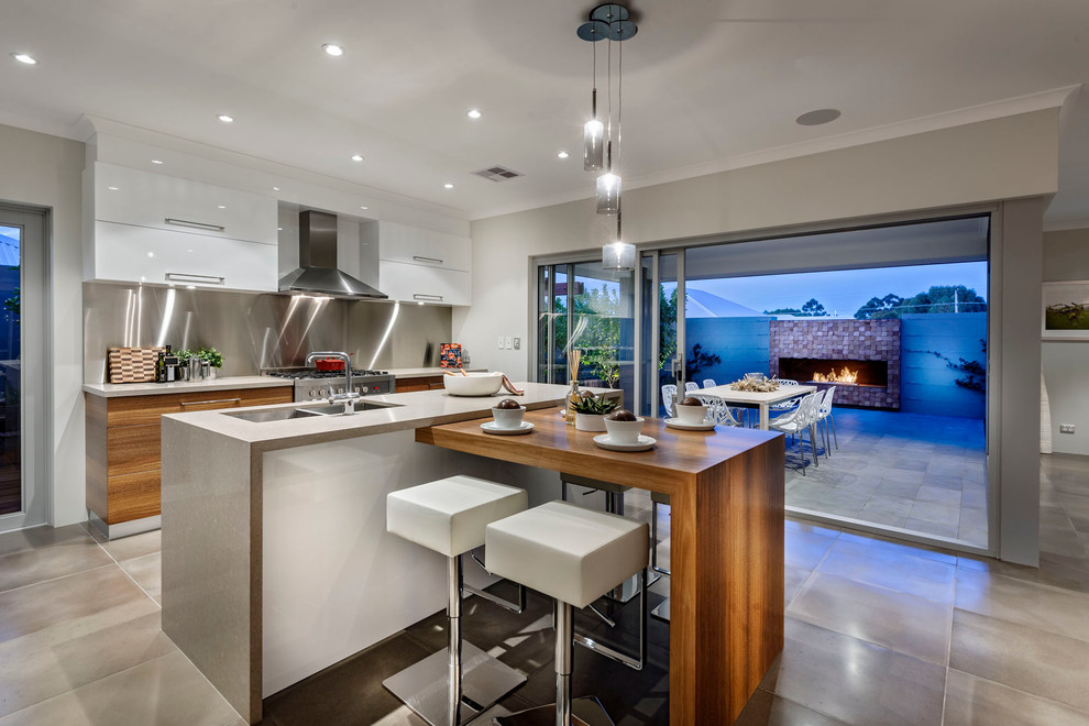 Exempel på ett modernt kök, med en undermonterad diskho, släta luckor, vita skåp, stänkskydd med metallisk yta, stänkskydd i metallkakel, rostfria vitvaror, betonggolv och en köksö