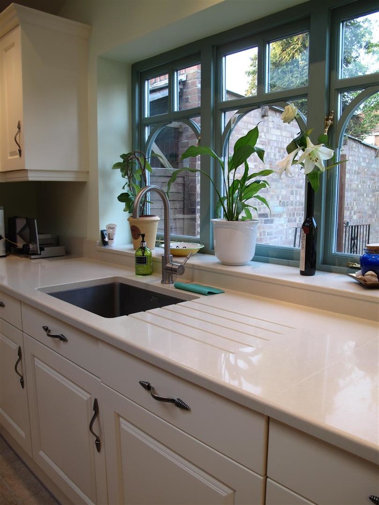 Example of a classic u-shaped eat-in kitchen design in London with an undermount sink, raised-panel cabinets, beige cabinets and quartz countertops