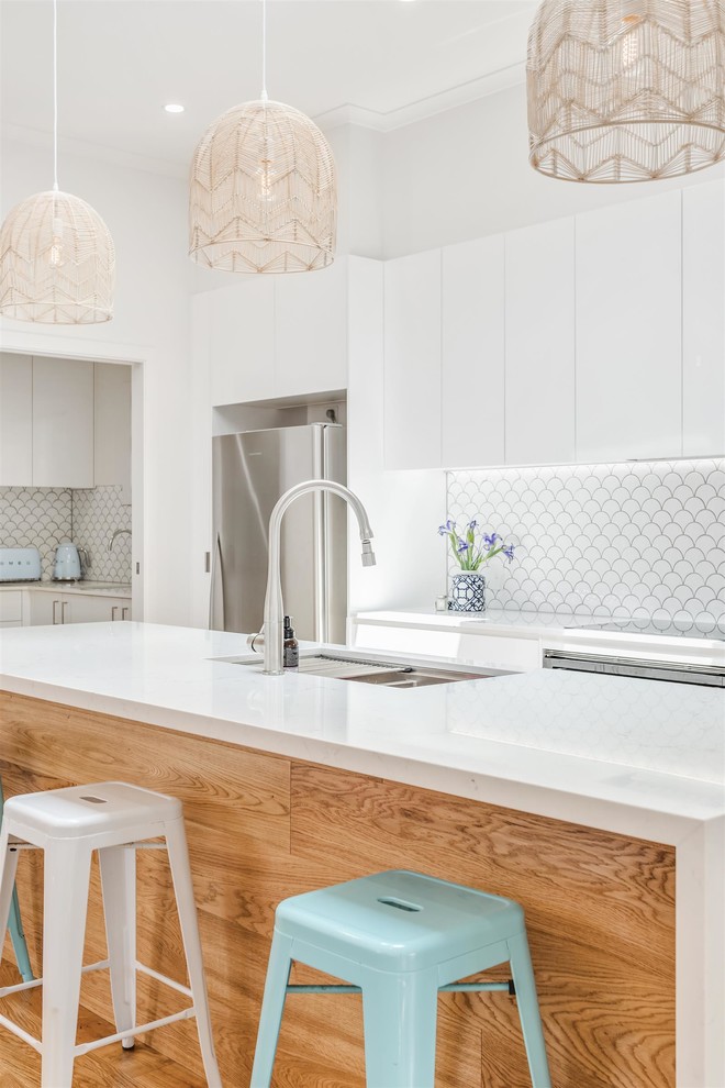 Large trendy galley medium tone wood floor and brown floor kitchen pantry photo in Gold Coast - Tweed with an undermount sink, flat-panel cabinets, white cabinets, quartzite countertops, white backsplash, ceramic backsplash, colored appliances and an island