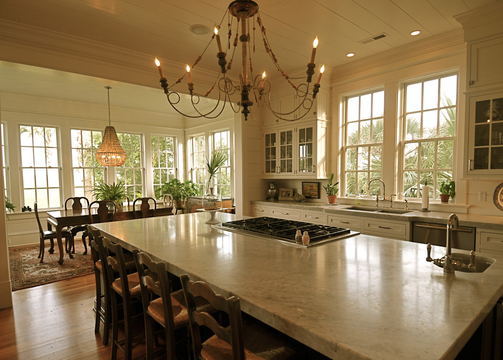 На фото: кухня в стиле рустика с стеклянными фасадами, обеденным столом, белыми фасадами и мраморной столешницей с