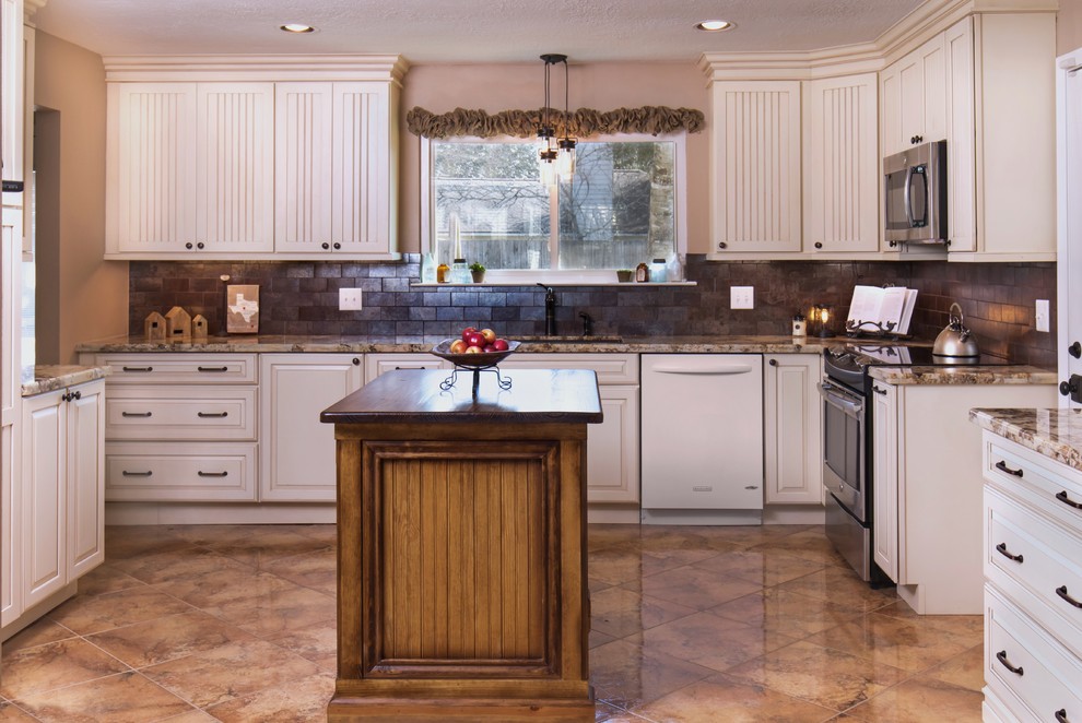 Inspiration for a large rural u-shaped kitchen in Houston with beaded cabinets, granite worktops, a submerged sink, white cabinets, brown splashback, metro tiled splashback, stainless steel appliances, ceramic flooring, an island and brown floors.