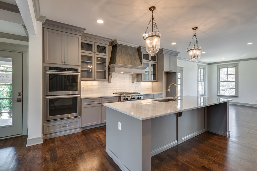 Large elegant u-shaped dark wood floor open concept kitchen photo in Nashville with a single-bowl sink, gray cabinets, granite countertops, white backsplash, stainless steel appliances and an island