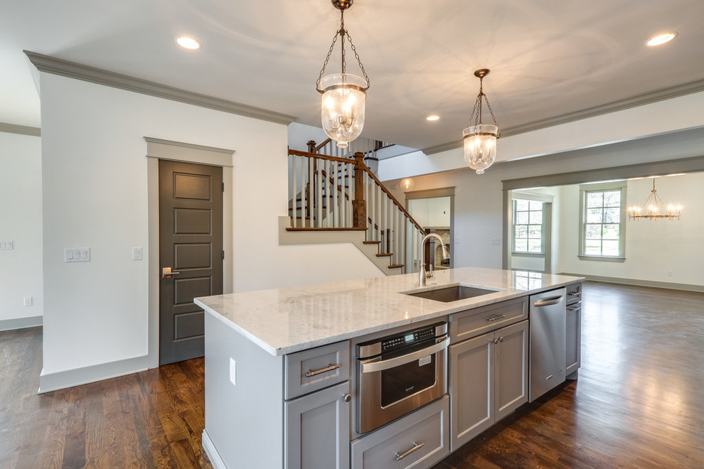 Inspiration for a large traditional u-shaped open plan kitchen in Nashville with grey cabinets, granite worktops, an island, a single-bowl sink, grey splashback, stainless steel appliances and dark hardwood flooring.