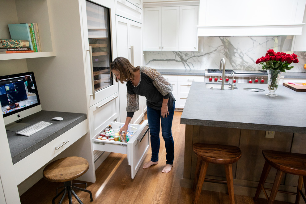 Cette photo montre une grande cuisine ouverte moderne en U avec un évier encastré, un placard à porte shaker, des portes de placard blanches, un plan de travail en quartz modifié, une crédence blanche, une crédence en marbre, un électroménager en acier inoxydable, un sol en bois brun, îlot, un sol marron et un plan de travail gris.