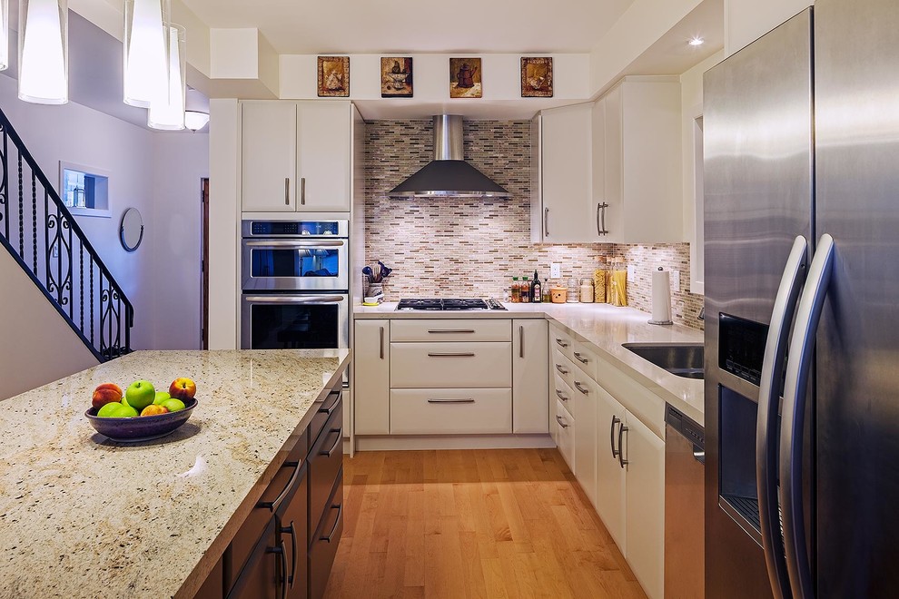 Exemple d'une cuisine chic en L avec des portes de placard blanches, une crédence marron, une crédence en carreau briquette et un électroménager en acier inoxydable.