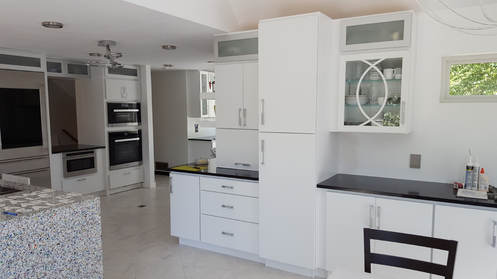 Modern inredning av ett mycket stort linjärt kök och matrum, med släta luckor, vita skåp, vitt stänkskydd, rostfria vitvaror, marmorgolv, en köksö, grått golv och bänkskiva i kvarts