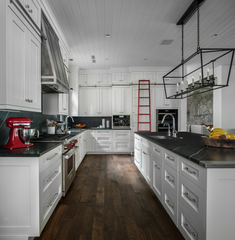 Klassische Küche in L-Form mit Unterbauwaschbecken, Schrankfronten im Shaker-Stil, weißen Schränken, dunklem Holzboden, Kücheninsel und braunem Boden in Sonstige