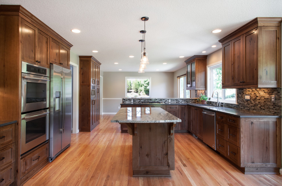 Photo of a large rustic l-shaped kitchen/diner in Portland with a single-bowl sink, shaker cabinets, medium wood cabinets, engineered stone countertops, mosaic tiled splashback, stainless steel appliances, light hardwood flooring, an island, blue splashback and beige floors.