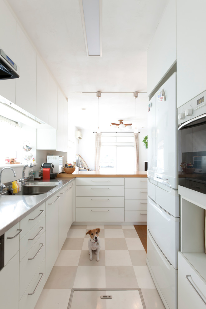 This is an example of a medium sized l-shaped open plan kitchen in Tokyo with an integrated sink, flat-panel cabinets, white cabinets, stainless steel worktops, white splashback, white appliances, ceramic flooring and no island.