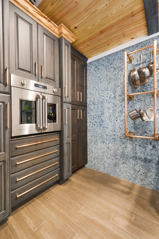 Idéer för att renovera ett litet eklektiskt vit vitt kök, med en rustik diskho, luckor med upphöjd panel, blå skåp, bänkskiva i koppar, blått stänkskydd, glaspanel som stänkskydd, rostfria vitvaror, bambugolv, en köksö och brunt golv