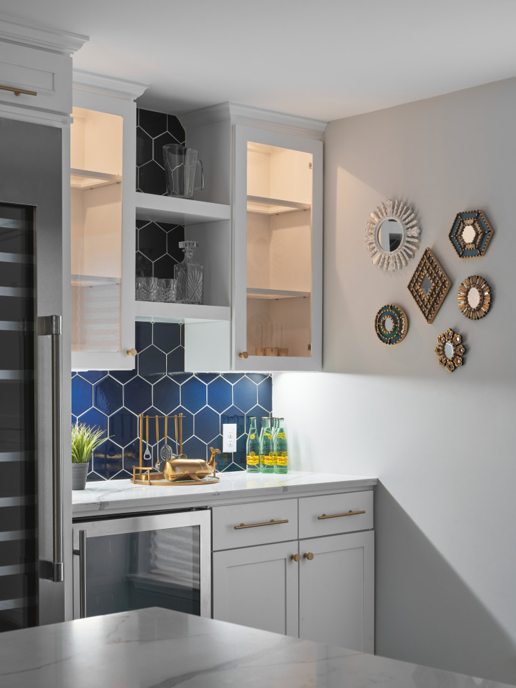 Exemple d'une grande cuisine américaine linéaire chic avec des portes de placard blanches, une crédence bleue, une crédence en céramique, îlot, un sol gris et un plan de travail blanc.