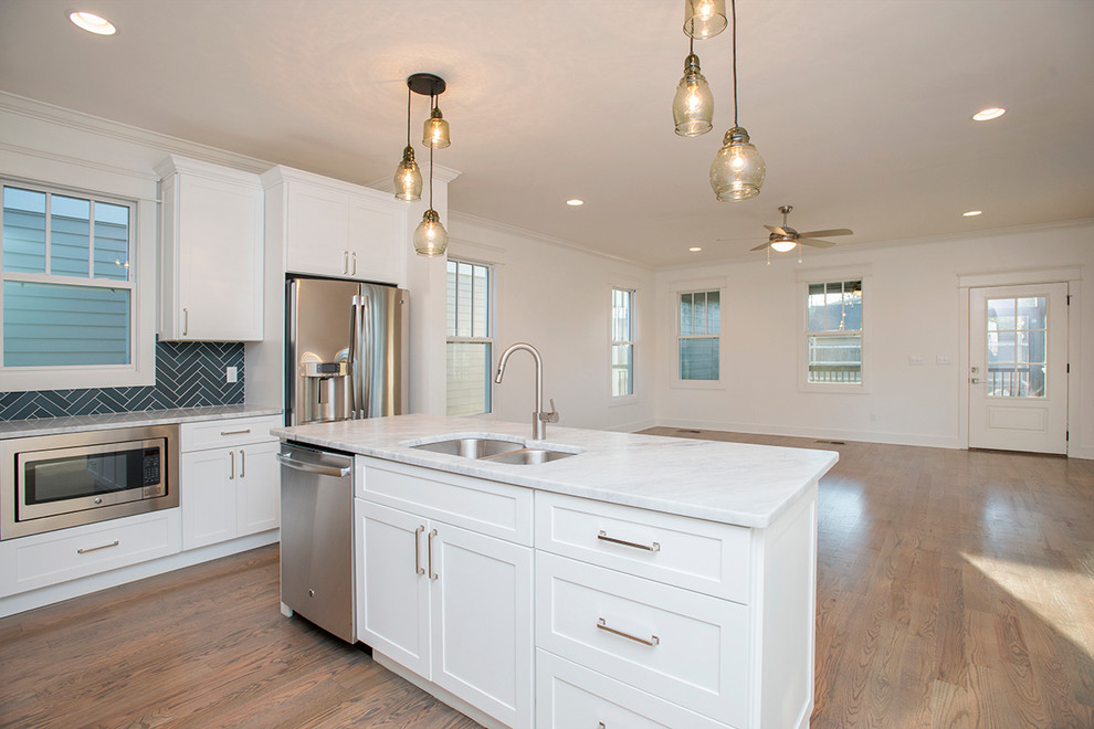 Foto di una cucina minimalista di medie dimensioni con lavello a doppia vasca, ante bianche, top in granito, paraspruzzi grigio, elettrodomestici in acciaio inossidabile e pavimento in legno massello medio
