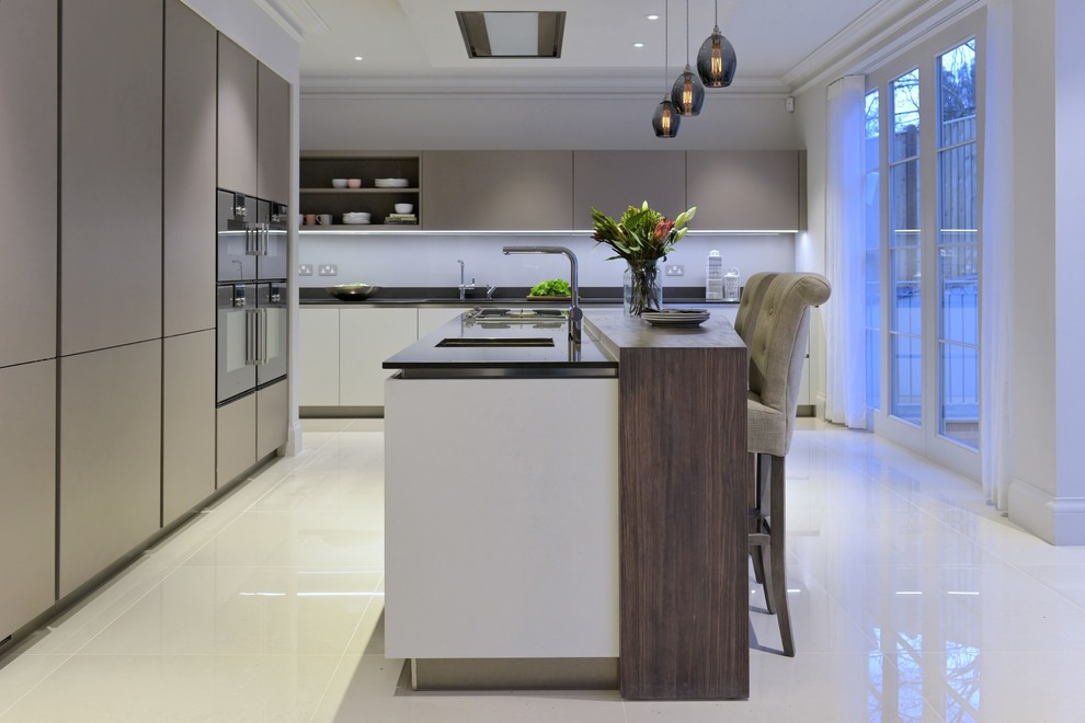 Photo of a medium sized contemporary l-shaped kitchen/diner in Gloucestershire with a submerged sink, flat-panel cabinets, grey cabinets, composite countertops, white splashback, glass sheet splashback, stainless steel appliances, porcelain flooring and an island.