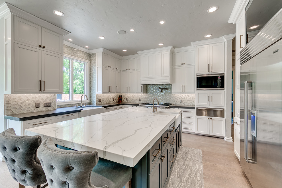 Design ideas for a large classic l-shaped enclosed kitchen in Nashville with a belfast sink, recessed-panel cabinets, white cabinets, engineered stone countertops, grey splashback, metal splashback, stainless steel appliances, light hardwood flooring and an island.