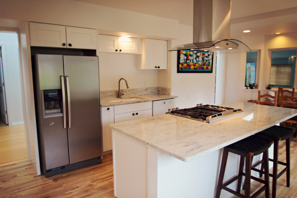 Mid-sized transitional single-wall linoleum floor eat-in kitchen photo in Seattle with white cabinets, granite countertops, stainless steel appliances, an island, an undermount sink, shaker cabinets, white backsplash and stone slab backsplash