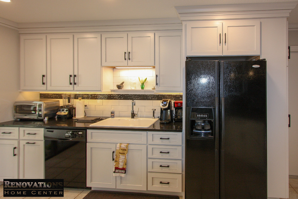 Example of a mid-sized minimalist galley kitchen design in Tampa with a drop-in sink, shaker cabinets, white cabinets, quartz countertops, white backsplash, ceramic backsplash, black appliances, no island and black countertops