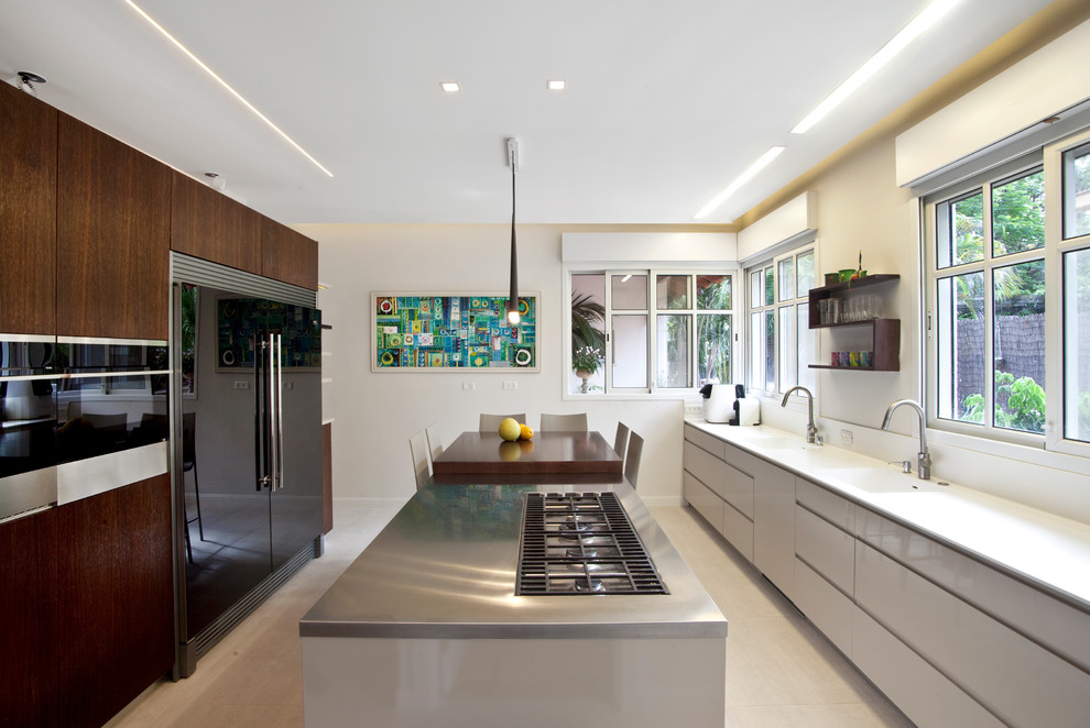 Zweizeilige Moderne Wohnküche mit integriertem Waschbecken, flächenbündigen Schrankfronten, weißen Schränken, schwarzen Elektrogeräten und Kücheninsel in Tel Aviv