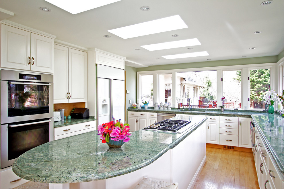 Example of a mid-sized classic u-shaped light wood floor and brown floor enclosed kitchen design in DC Metro with raised-panel cabinets, white cabinets, granite countertops, an island, a double-bowl sink, stainless steel appliances and green countertops