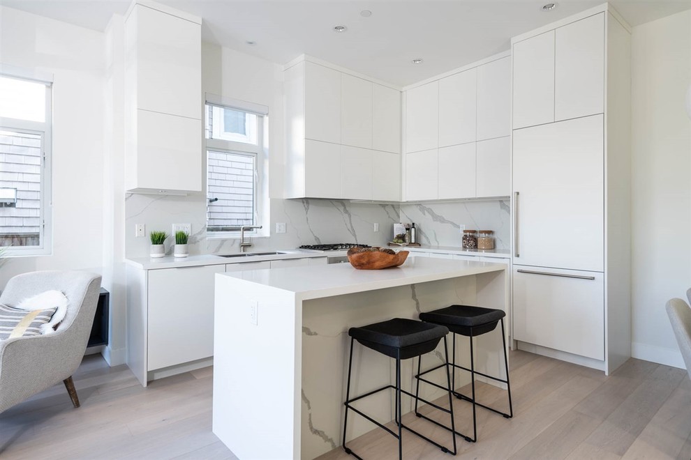 Medium sized contemporary l-shaped open plan kitchen in Vancouver with flat-panel cabinets, white cabinets, engineered stone countertops, an island and white worktops.