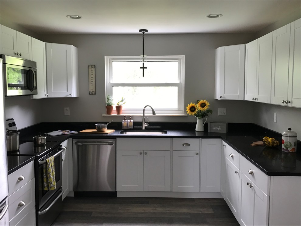 Example of a mid-sized transitional u-shaped dark wood floor and brown floor eat-in kitchen design in Other with an undermount sink, shaker cabinets, white cabinets, quartz countertops, stainless steel appliances and no island