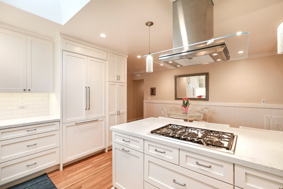 Medium sized traditional kitchen/diner in San Francisco with shaker cabinets, white cabinets, engineered stone countertops, white splashback, metro tiled splashback, stainless steel appliances, a breakfast bar and white worktops.