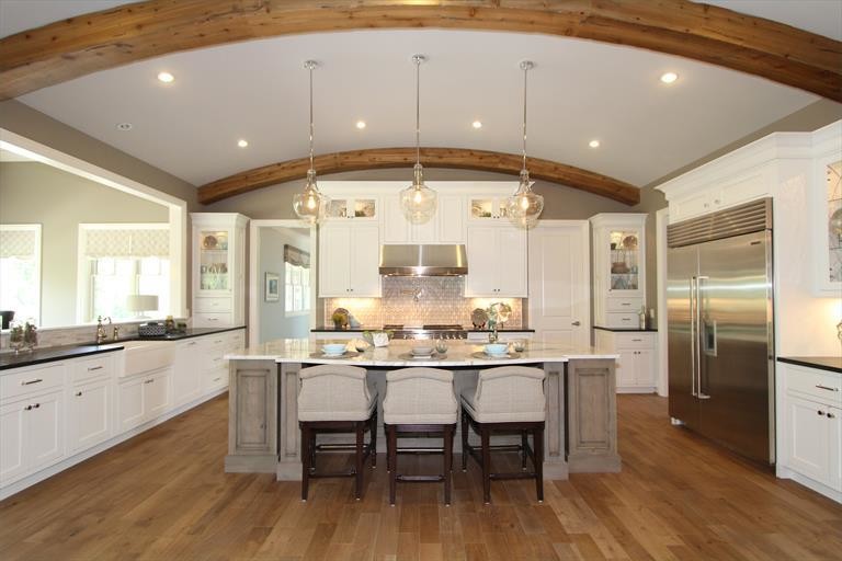 Inspiration for a large transitional medium tone wood floor eat-in kitchen remodel in Cincinnati with an undermount sink, onyx countertops, beige backsplash, stone slab backsplash, stainless steel appliances and two islands