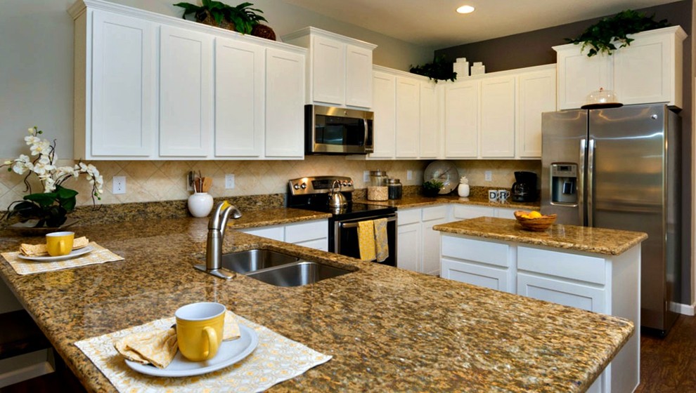 Klassisk inredning av ett mellanstort u-kök, med en dubbel diskho, skåp i shakerstil, vita skåp, granitbänkskiva, beige stänkskydd, stänkskydd i keramik, rostfria vitvaror, mörkt trägolv, en köksö och brunt golv
