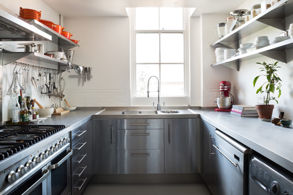 Example of a small urban u-shaped kitchen design in London with a double-bowl sink, flat-panel cabinets, stainless steel cabinets, concrete countertops, white backsplash, subway tile backsplash, stainless steel appliances and no island