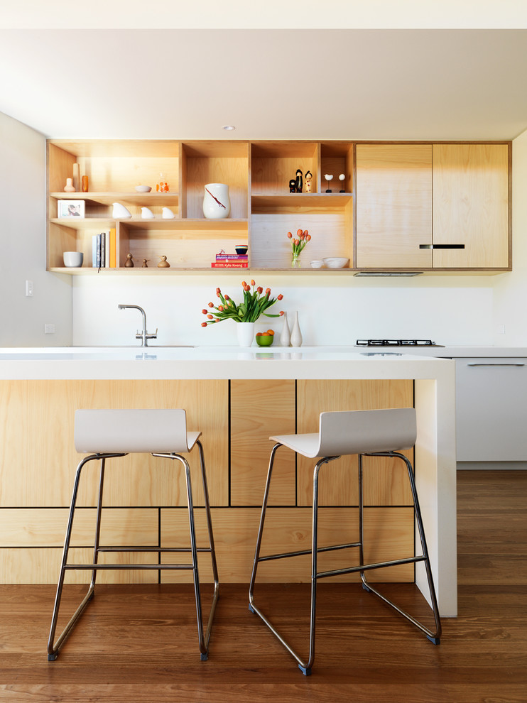 Idée de décoration pour une cuisine design en bois clair avec un plan de travail en quartz modifié et îlot.