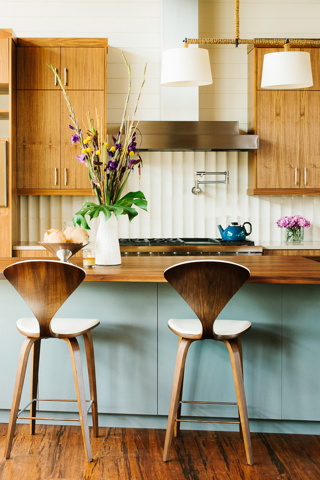 オースティンにあるミッドセンチュリースタイルのおしゃれなキッチン (フラットパネル扉のキャビネット、中間色木目調キャビネット、白いキッチンパネル) の写真