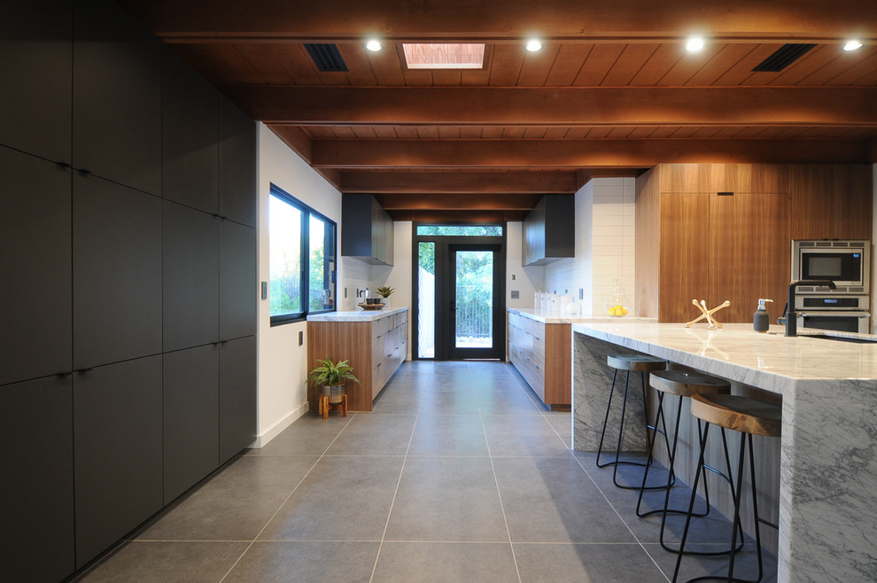 Photo of a large modern kitchen in Phoenix with a submerged sink, flat-panel cabinets, medium wood cabinets, marble worktops, white splashback, stone slab splashback, integrated appliances, an island, grey floors and white worktops.