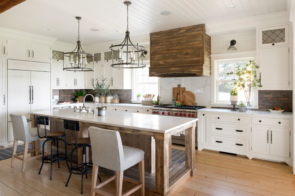 Inspiration for a large rural l-shaped kitchen in Minneapolis with a belfast sink, white cabinets, multi-coloured splashback, brick splashback, stainless steel appliances, an island and white worktops.