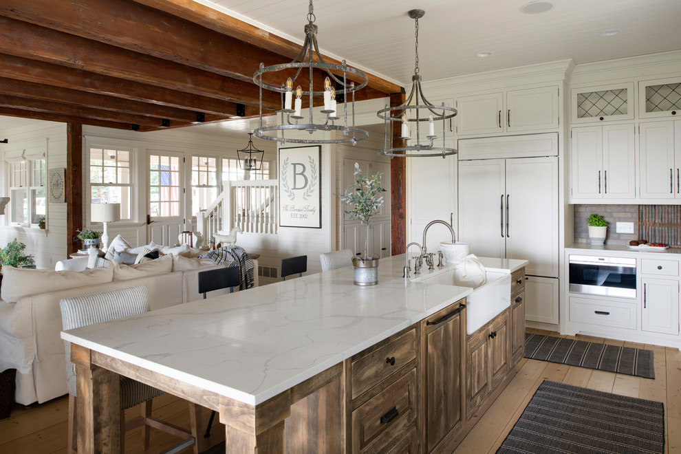Large farmhouse l-shaped kitchen in Minneapolis with a belfast sink, white cabinets, multi-coloured splashback, brick splashback, stainless steel appliances, an island and white worktops.